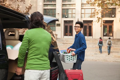 A student loading up his car, ready to go home for winter break. His mom is helping him.